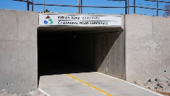 Angled view of the Chaparral Road Underpass entrance on the Indian Bend Wash Path, a concrete tunnel with a yellow-striped paved trail running through it.