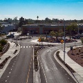 Roundabout with road signs, buildings, and Raintree Drive sign at dusk.