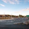 Roundabout with pedestrian crossings and surrounding commercial buildings.