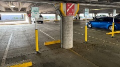 Interior of a public parking garage with marked parking spaces, support columns, and juror-only parking signs on Level 1.