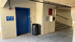 Parking garage interior showing an elevator, stairwell, and signage directing visitors to the City Jail and City Court levels.
