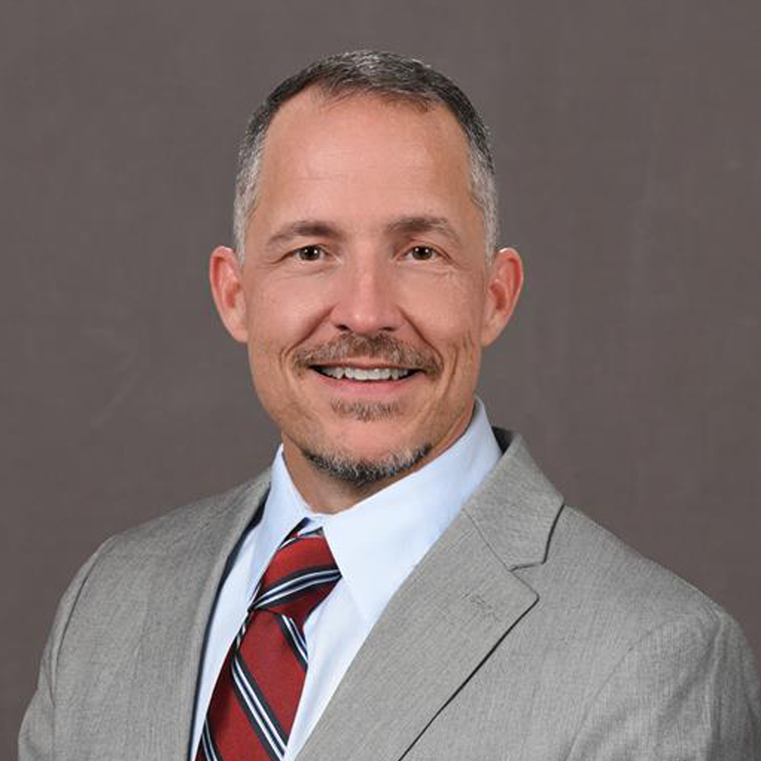 Portrait of Jeff Walther smiling in front of a plain background.