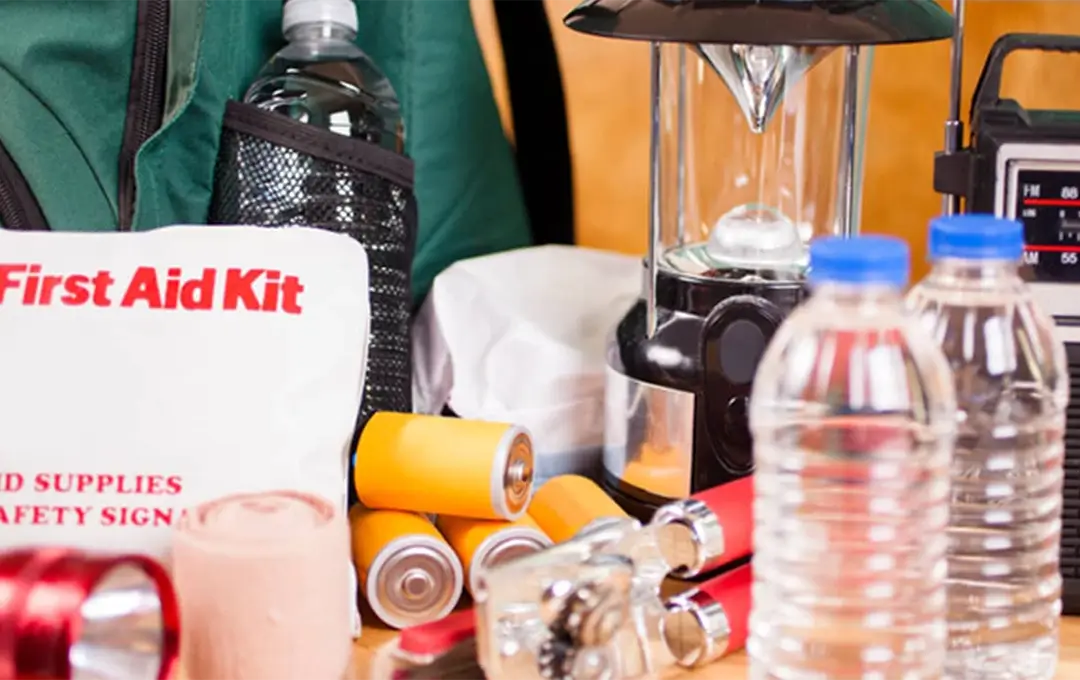 Assorted emergency supplies including water bottles, first aid kit, flashlight, batteries, and tools.