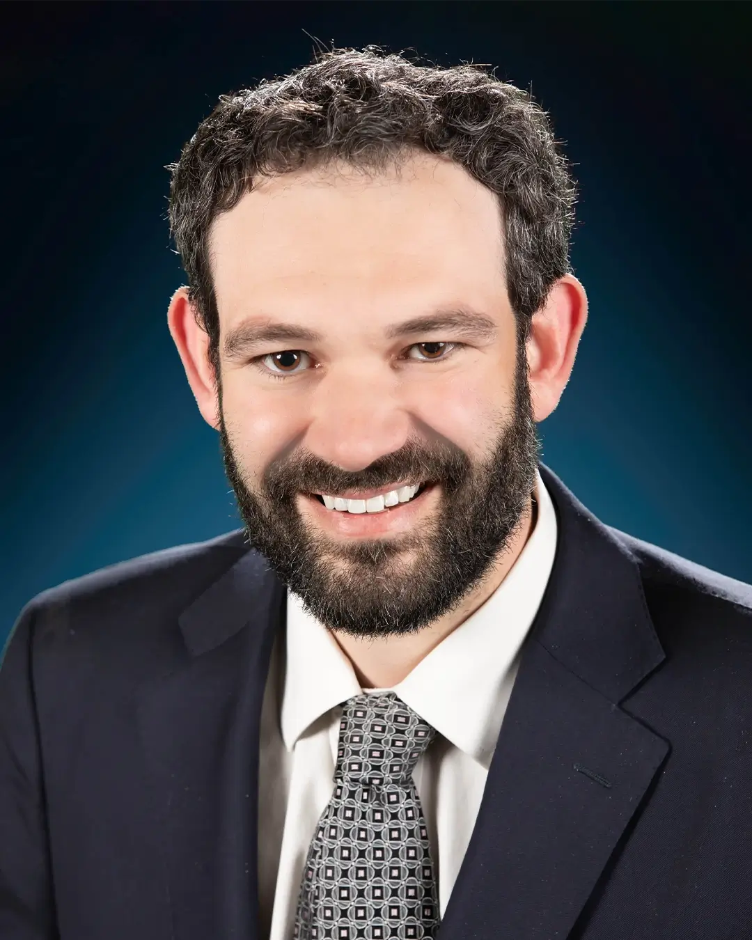 A portrait of Representative Alexander Kolodin smiling in front of a plain background.