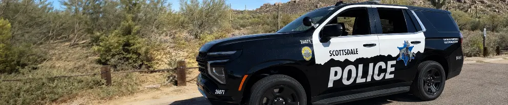 Black police SUV with City of Scottsdale Police decoratively printed on the car parked in a desert parking lot