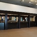 A dark wood bar with five serving windows, beer taps and a mirrored back wall in an empty event room.