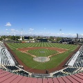 Wide view of Scottsdale Stadium from the upper level, showing the mowed field, grandstands, and distant mountains under a clear sky.