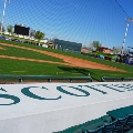 Scottsdale Stadium seating wall with Scottsdale painted in large green letters, overlooking the baseball field through a safety net.