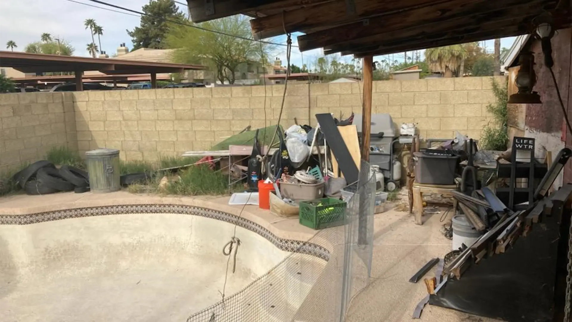 Debris and clutter next to an empty pool