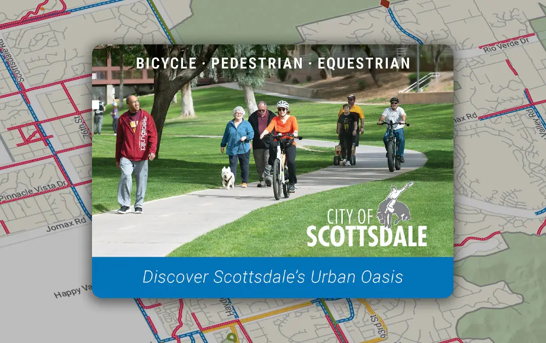 Group of people walking, biking, and scootering along a sunny green park pathway.