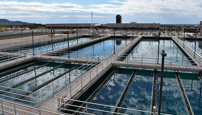 Large outdoor water treatment facility with multiple rectangular basins and metal walkways.