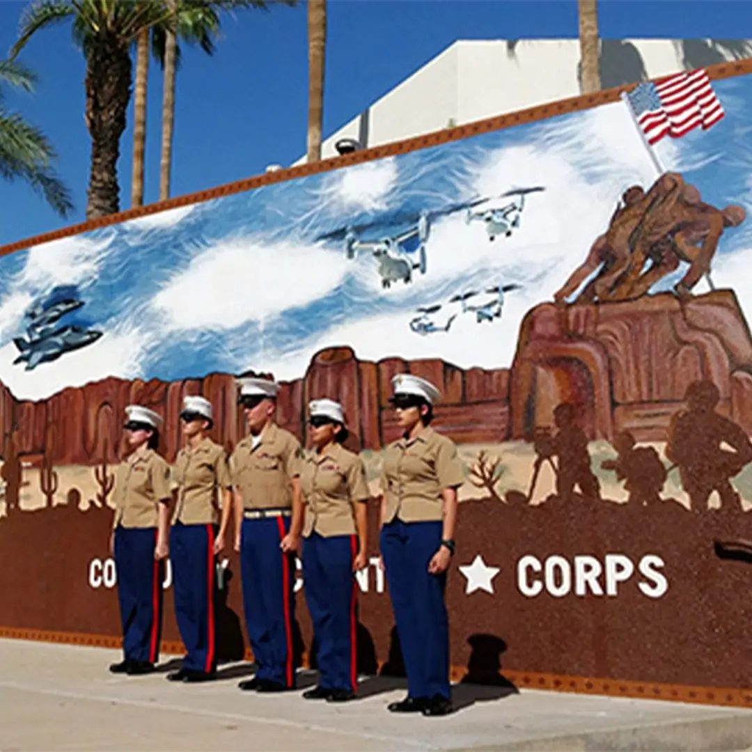 5 marines standing at attention in from of the marine mural